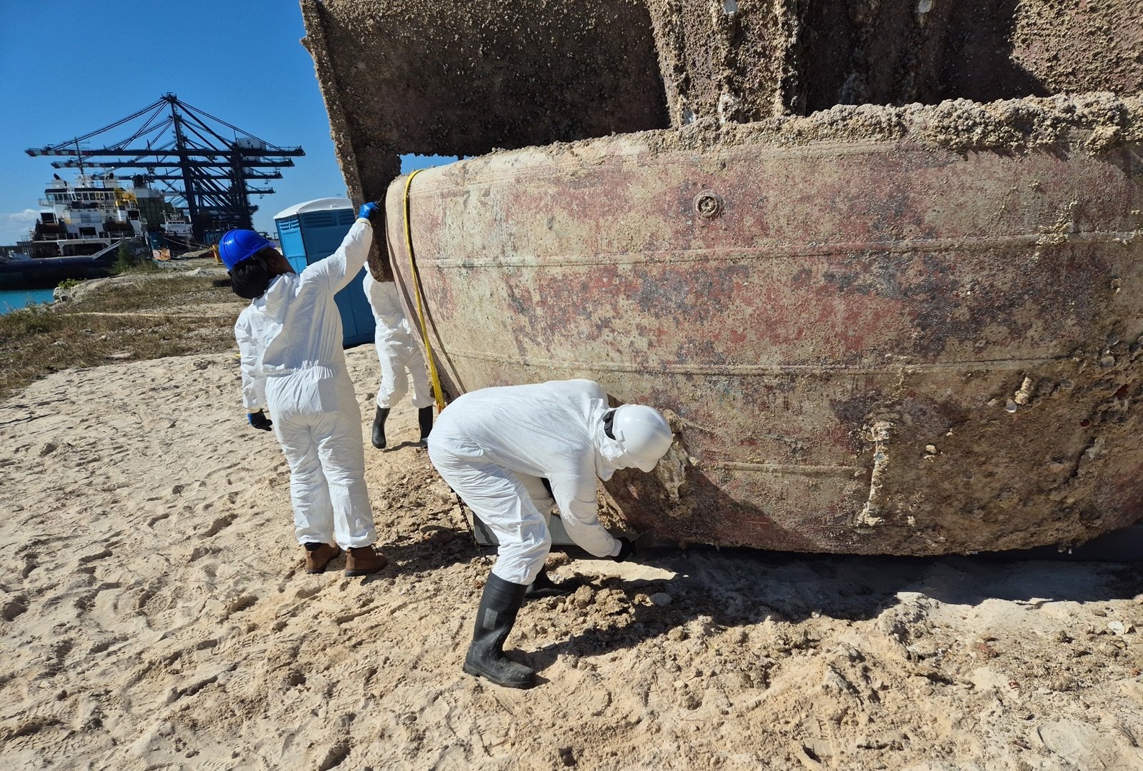OEM Bahamas crew in protective suits examining a hull section for hazmat handling
