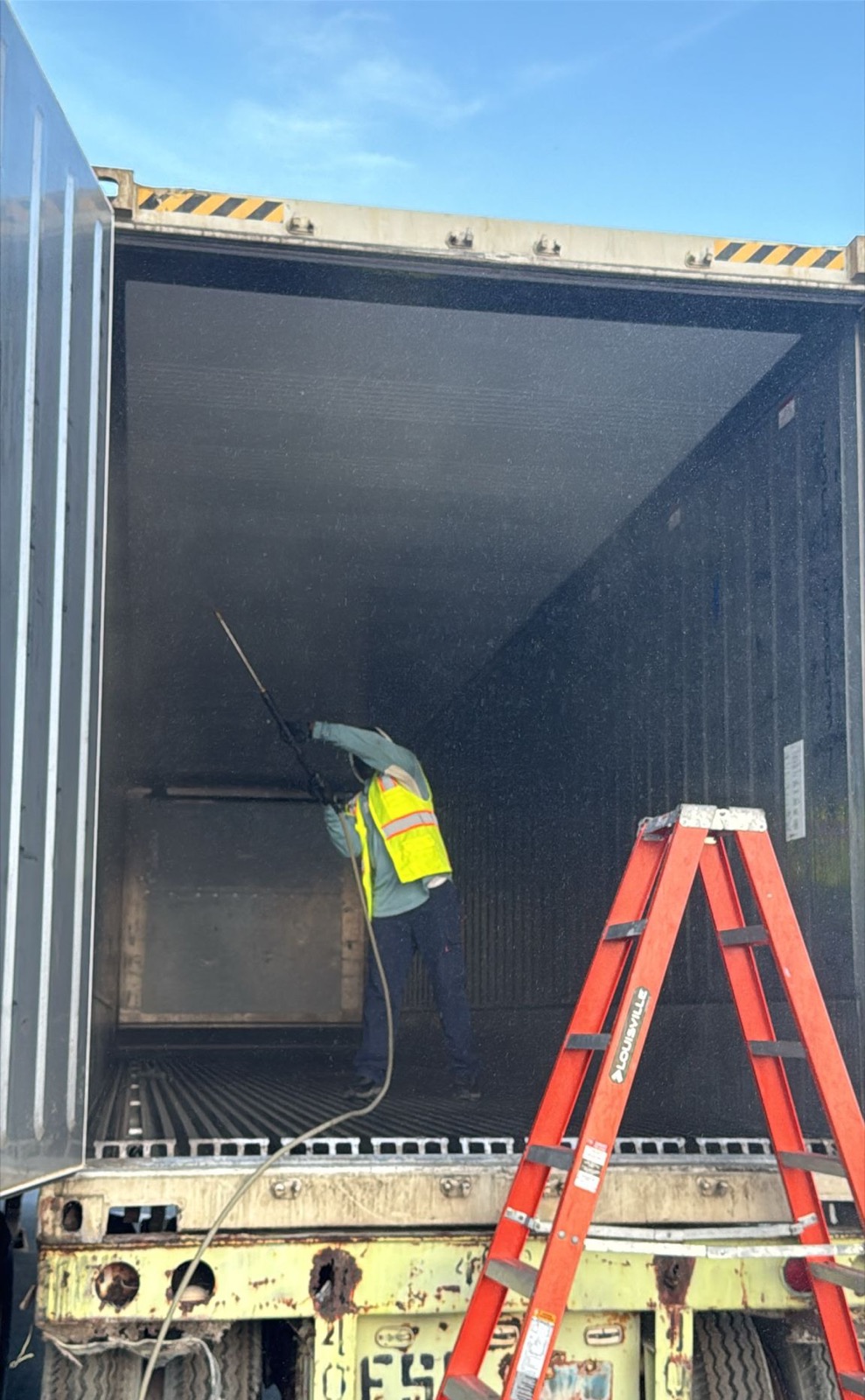Technician treating a container interior with a pressure sprayer