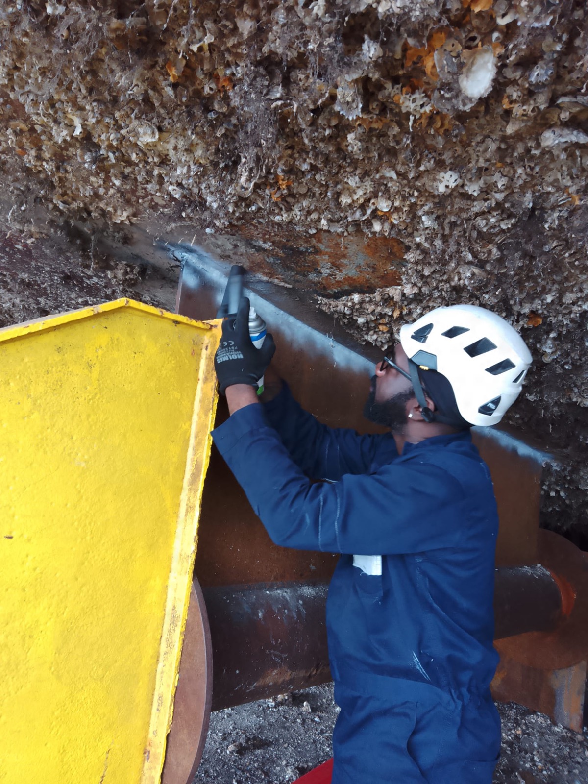 Technician applying penetrant dye to a weld during inspection