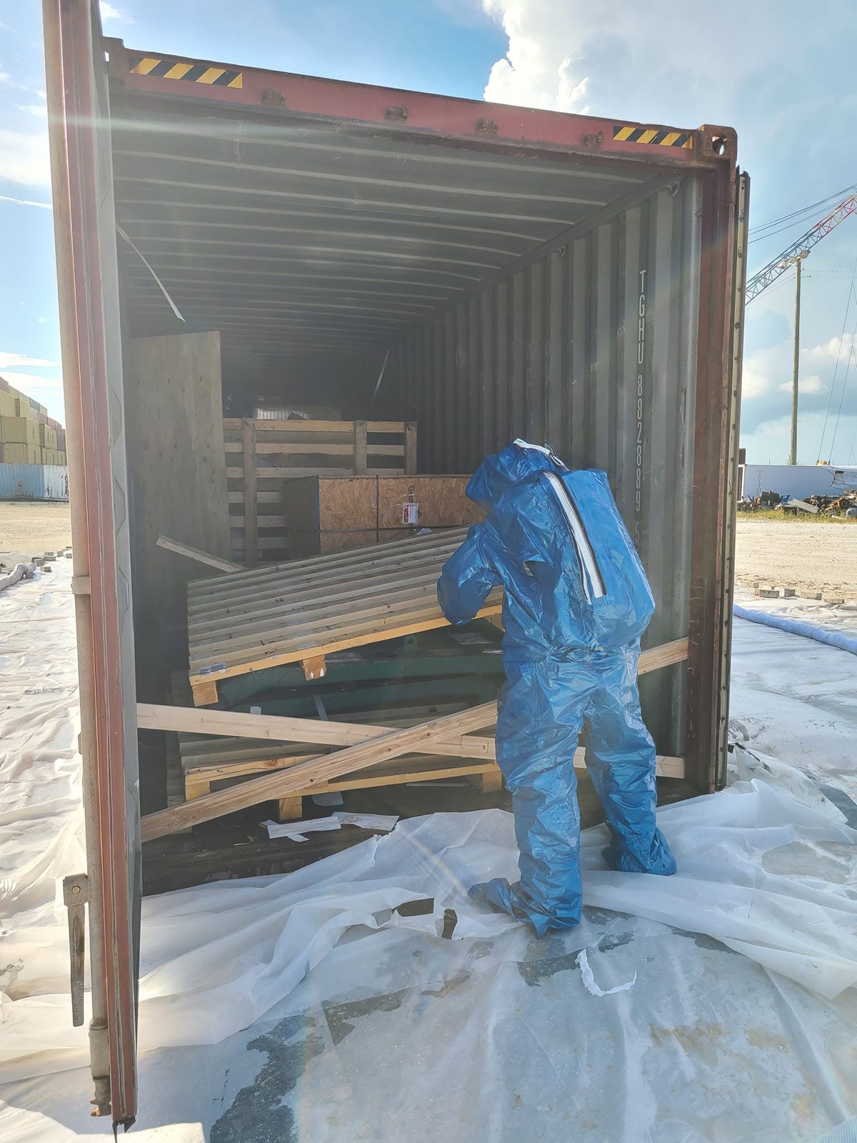 OEM Bahamas surveyor inspecting containerized cargo in protective suit